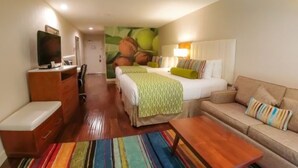 A hotel room with a bed, a sofa, a TV, a desk, and a colorful striped rug. - Hotel Indigo Anaheim by IHG (Anaheim)