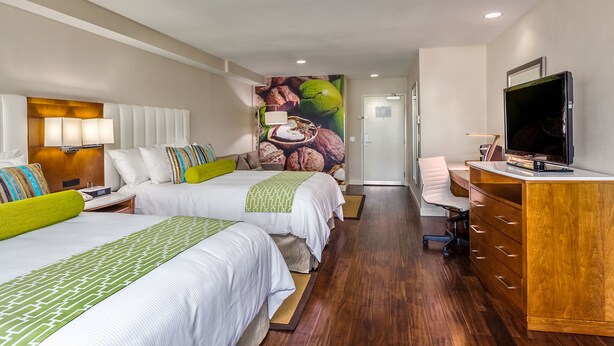 A hotel room with two beds, a desk, a television, and a mural on the wall. - Hotel Indigo Anaheim by IHG (Anaheim)
