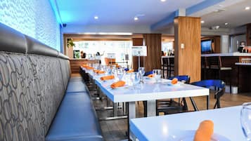 A restaurant with a long counter, blue chairs, and a patterned bench.
