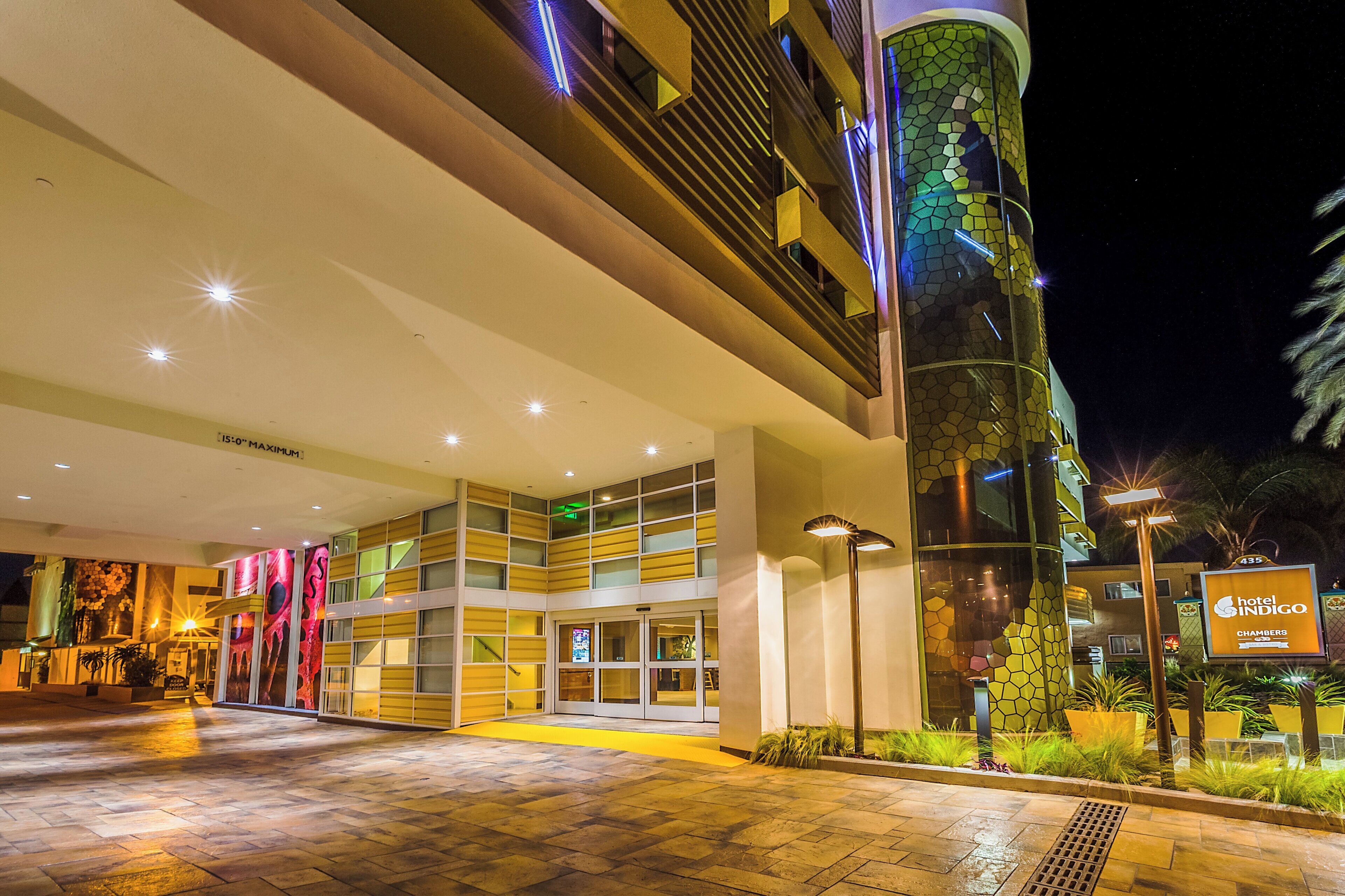 A hotel entrance with a modern design, featuring a glass facade, a ramp for accessibility, and a sign for the hotel.