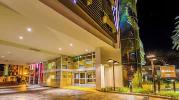 A hotel entrance with a modern design, featuring a glass facade, a ramp for accessibility, and a sign for the hotel.