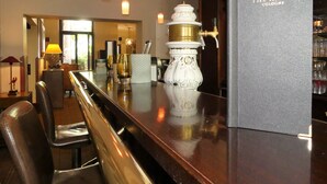 Et barområde med bardisk, en dekorativ hvid vase og en bog med titlen "The Ascot Cologne".