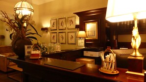 En receptionsdisk med blomstervase, indrammede billeder, et ur og en lampe.