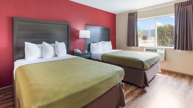A hotel room with two beds, red walls, and a large window with curtains. - Econo Lodge Painted Post - Corning (Painted Post)