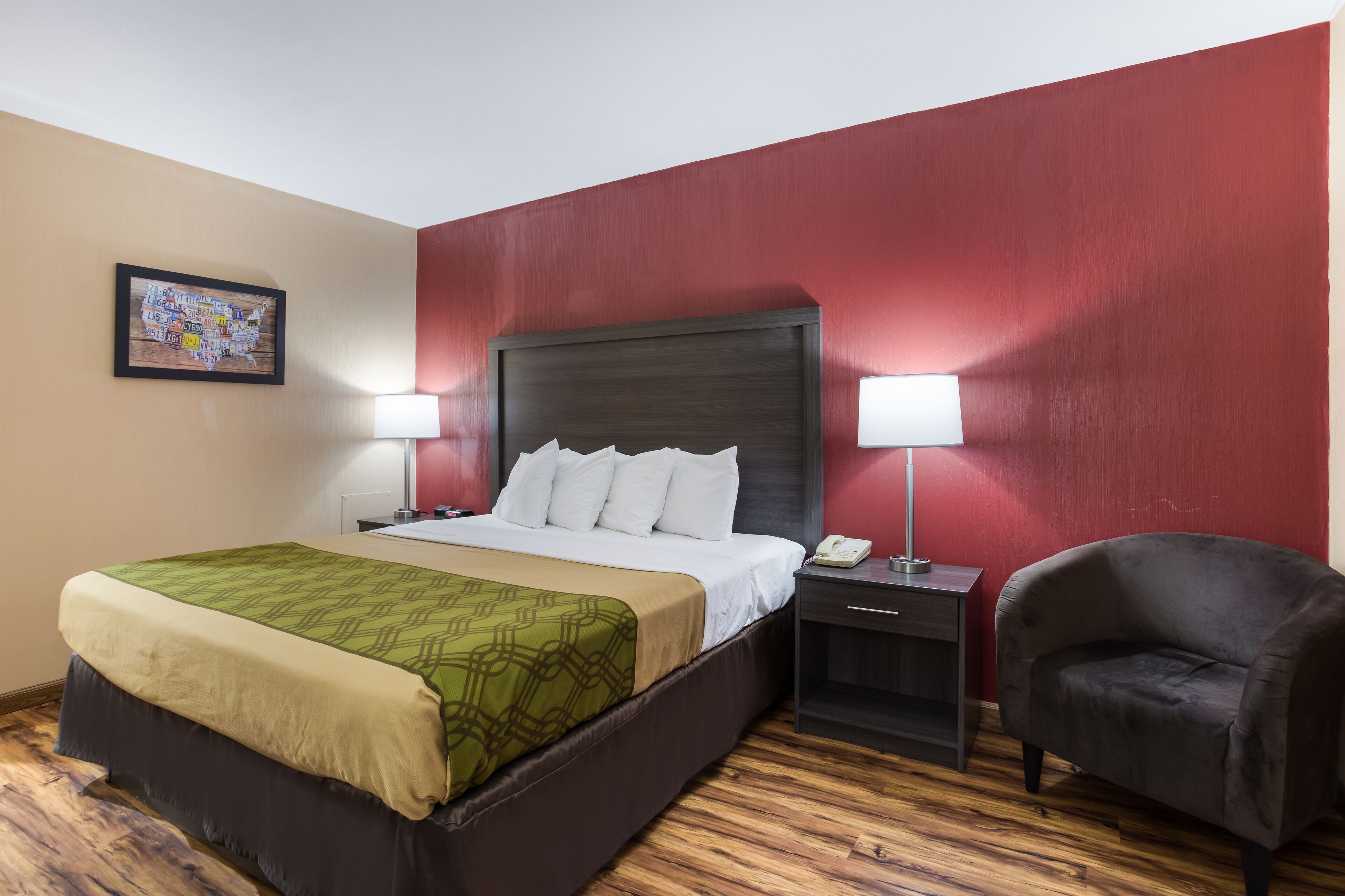 Una habitación de hotel con una cama, dos lámparas de noche, una silla y una mesita de noche.