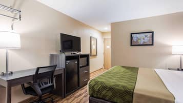 A hotel room with a bed, desk, chair, TV, and a painting on the wall.