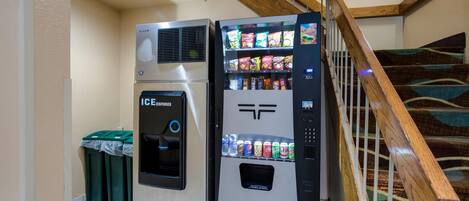 Ein Getränkeautomat mit Eis- und Getränkespender in der Nähe einer Treppe mit Holzwertlauf.