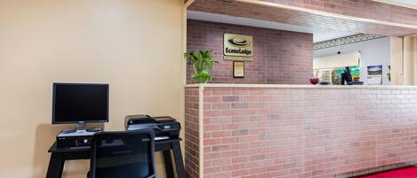 A reception desk with a computer, printer, and a sign for EconoLodge.