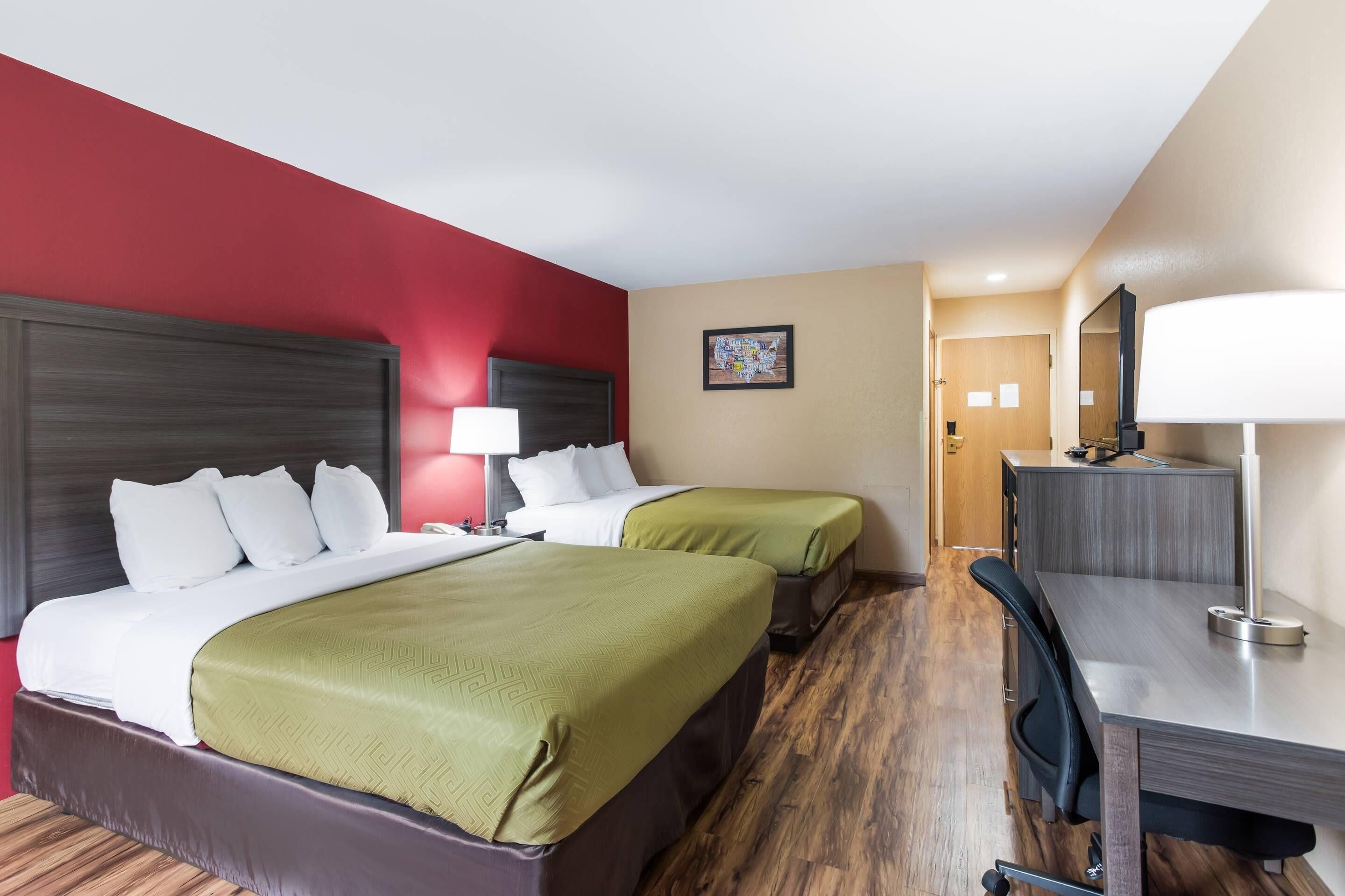 Una habitación de hotel con dos camas, un escritorio, una silla y un espejo.