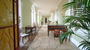 A spacious hallway with a piano, chairs, and potted plants. - Hintlesham Hall Hotel (Ipswich)