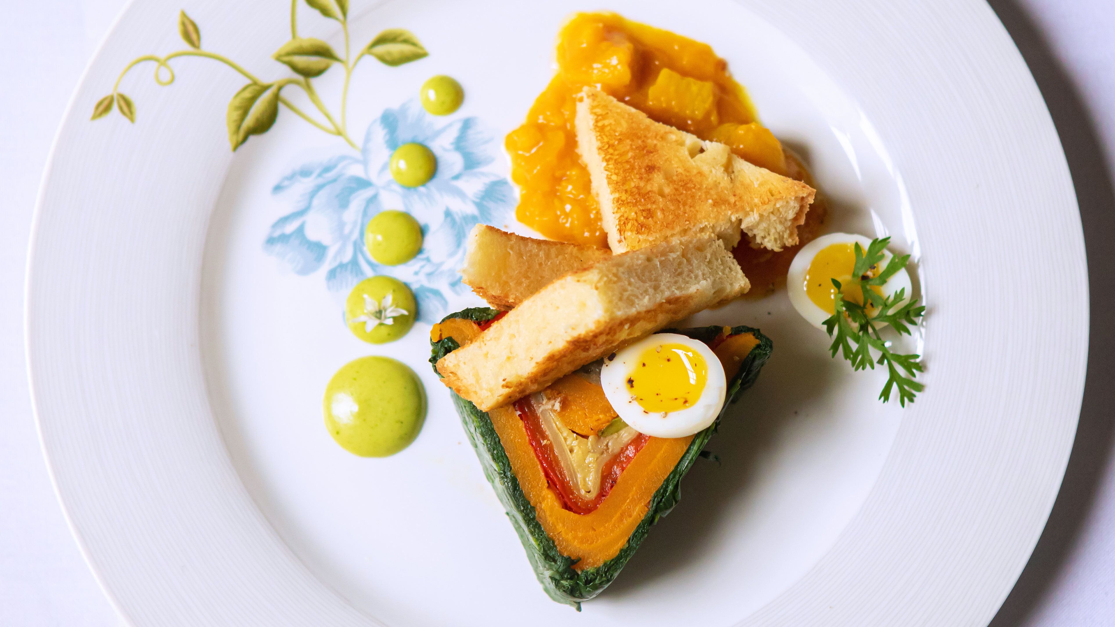 Un plato con calabaza rellena, rebanadas de tostada, un huevo duro y una porción de mango.