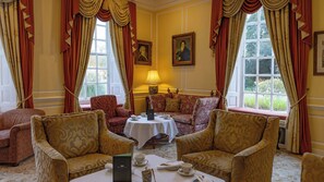 A room with a sofa set, a table with tea service, and a window with curtains. - Hintlesham Hall Hotel (Ipswich)