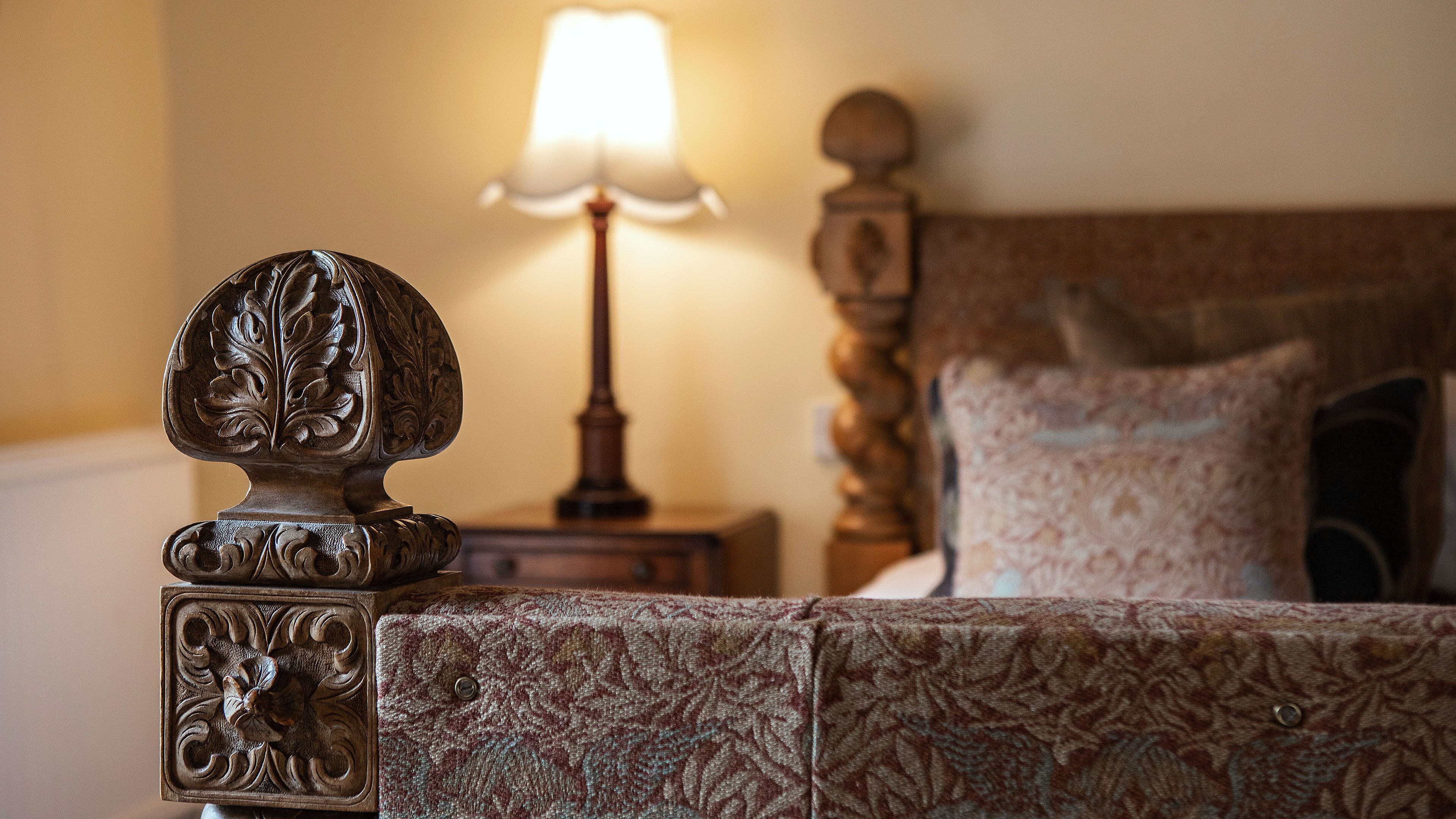 A bed with a decorative headboard, a bedside lamp, and a patterned pillow.