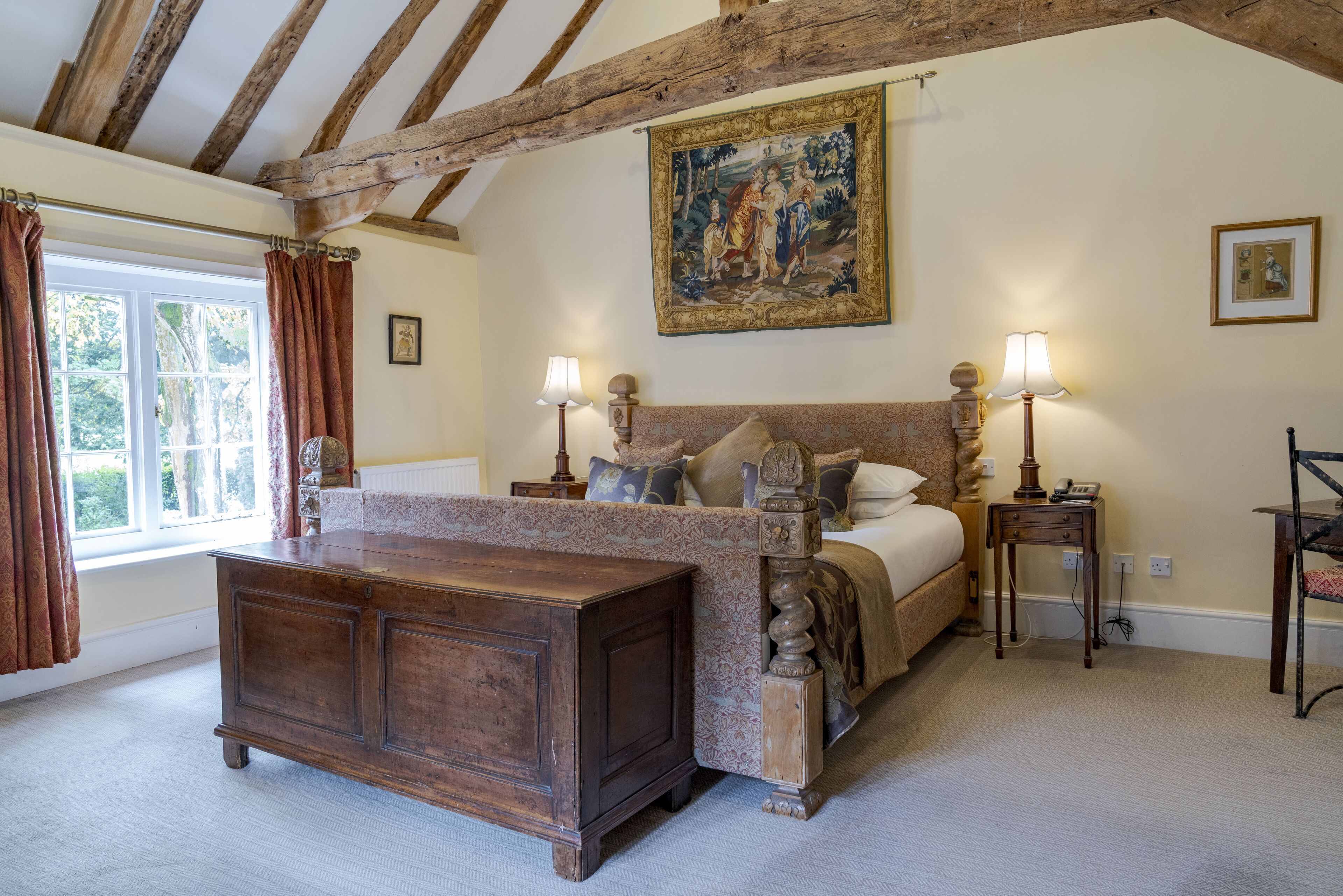 A bedroom with a large bed, a wooden dresser, and a painting on the wall.