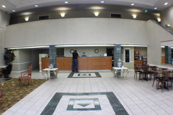 A lobby with a reception desk, chairs, tables, and a patterned floor.