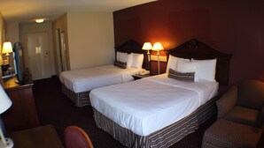 A hotel room with two beds, a desk, and a chair.