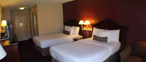 A hotel room with two beds, a desk, and a chair.