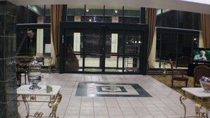 A lobby with a tiled floor, a reception desk, and a seating area with tables and chairs.