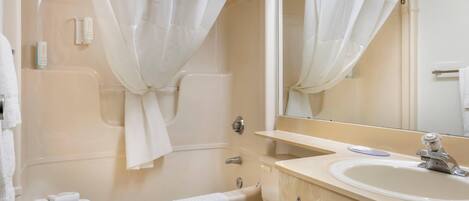 A bathroom with a bathtub, toilet, sink, and a mirror.