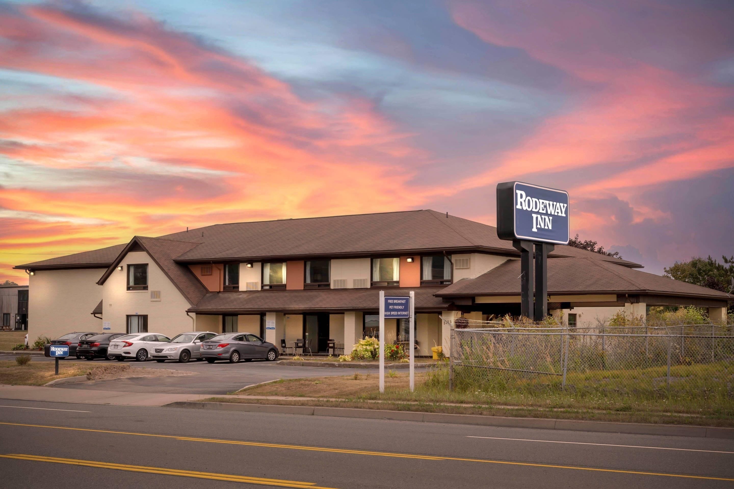 Un motel con un cartello che riporta 'Rodeway Inn' e un parcheggio con diverse auto.