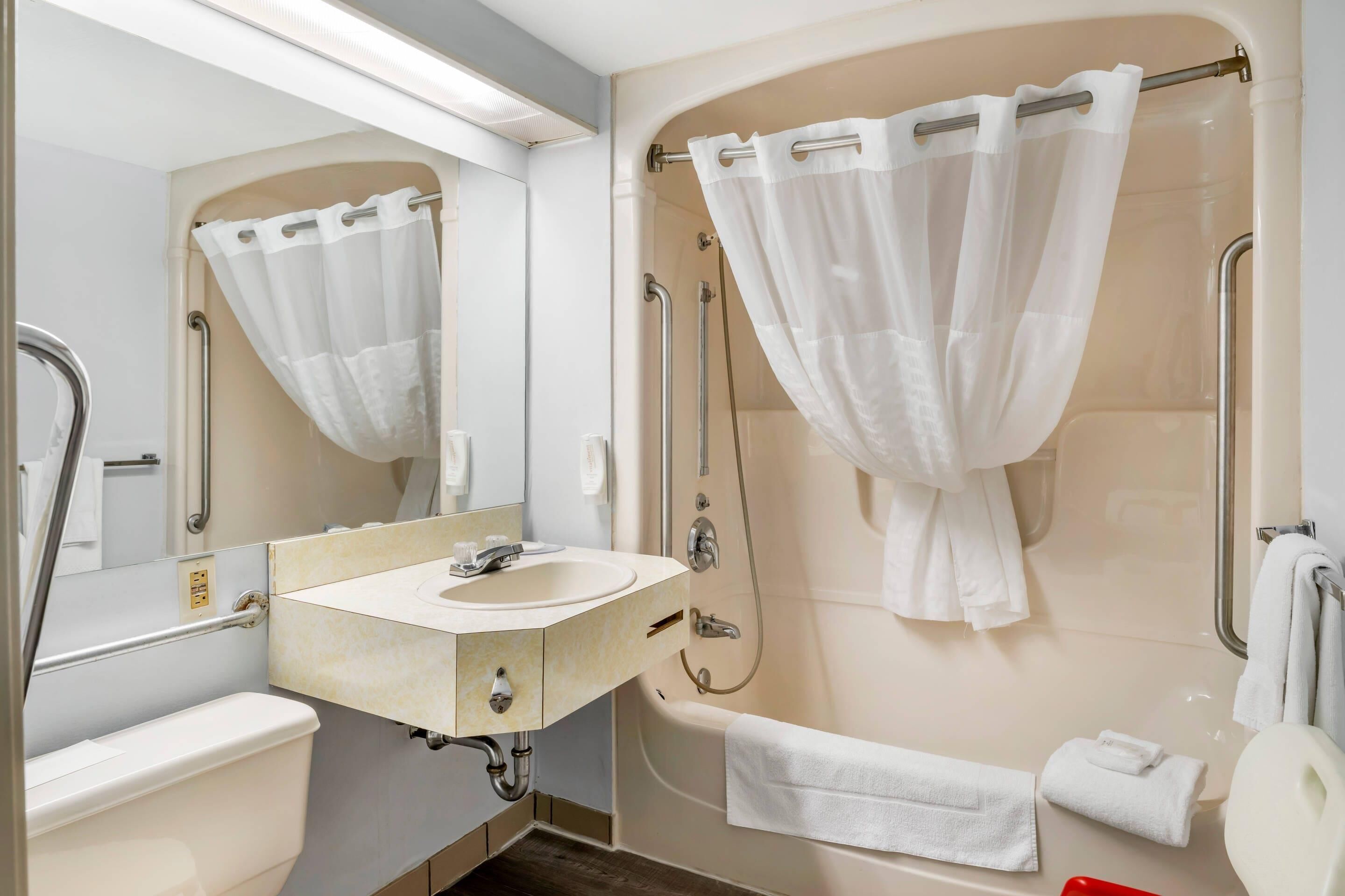 Un baño moderno con lavamanos, espejo, ducha e inodoro.
