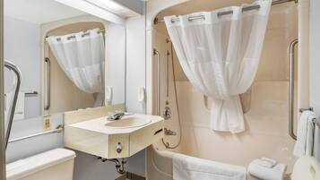 Un baño moderno con lavamanos, espejo, ducha e inodoro.