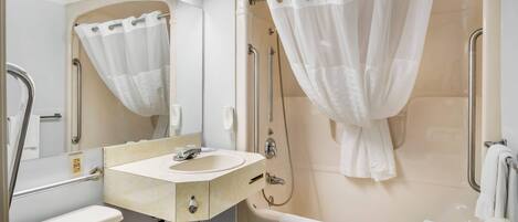 Un baño moderno con lavamanos, espejo, ducha e inodoro.