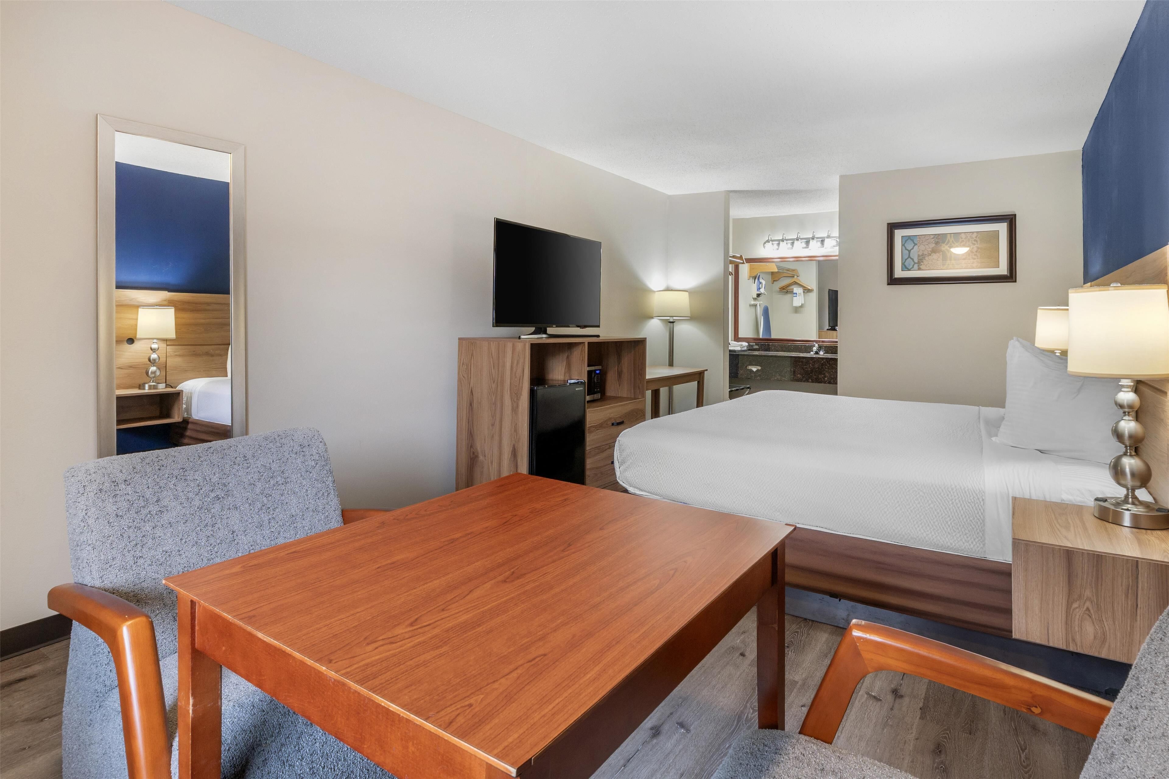 Une chambre d’hôtel avec un lit, une télévision, un bureau et une chaise.