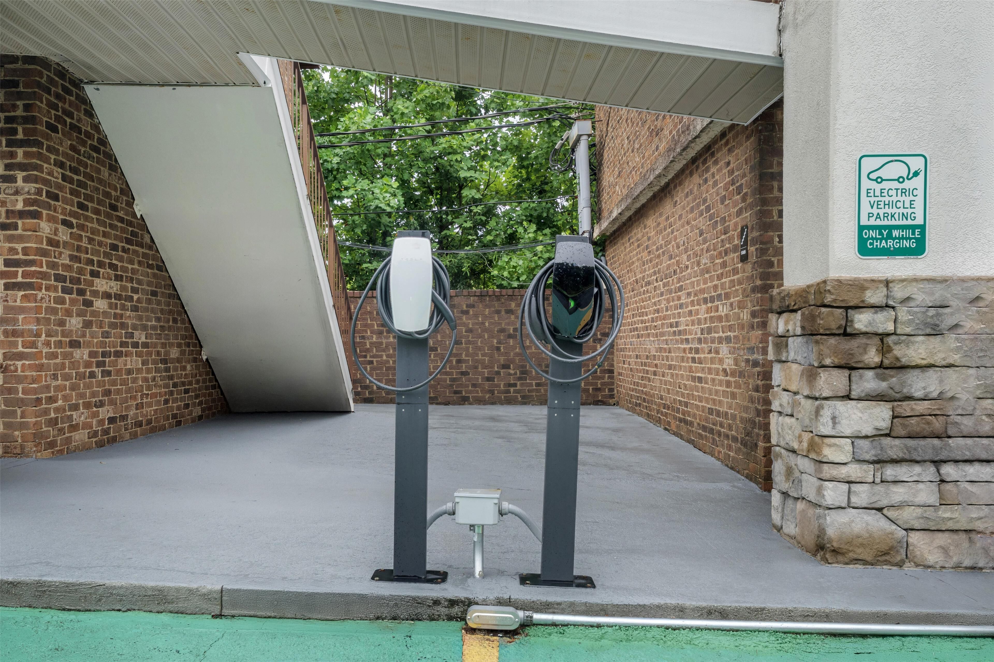 An electric vehicle charging station with a brick wall and a stone wall in the background.