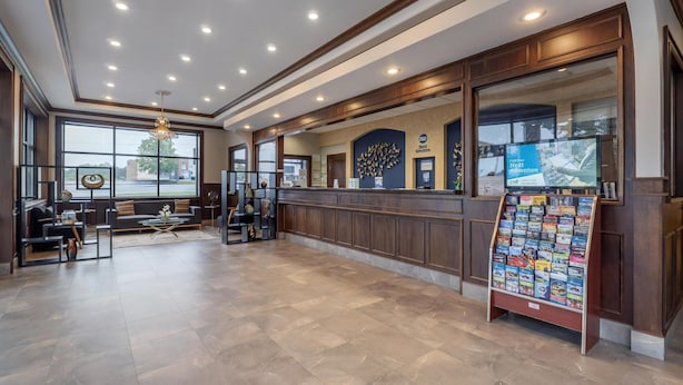 A reception area with a large window, a reception desk, a seating area with a sofa and coffee table, and a display stand with brochures. - Best Western Acworth Inn (Acworth)