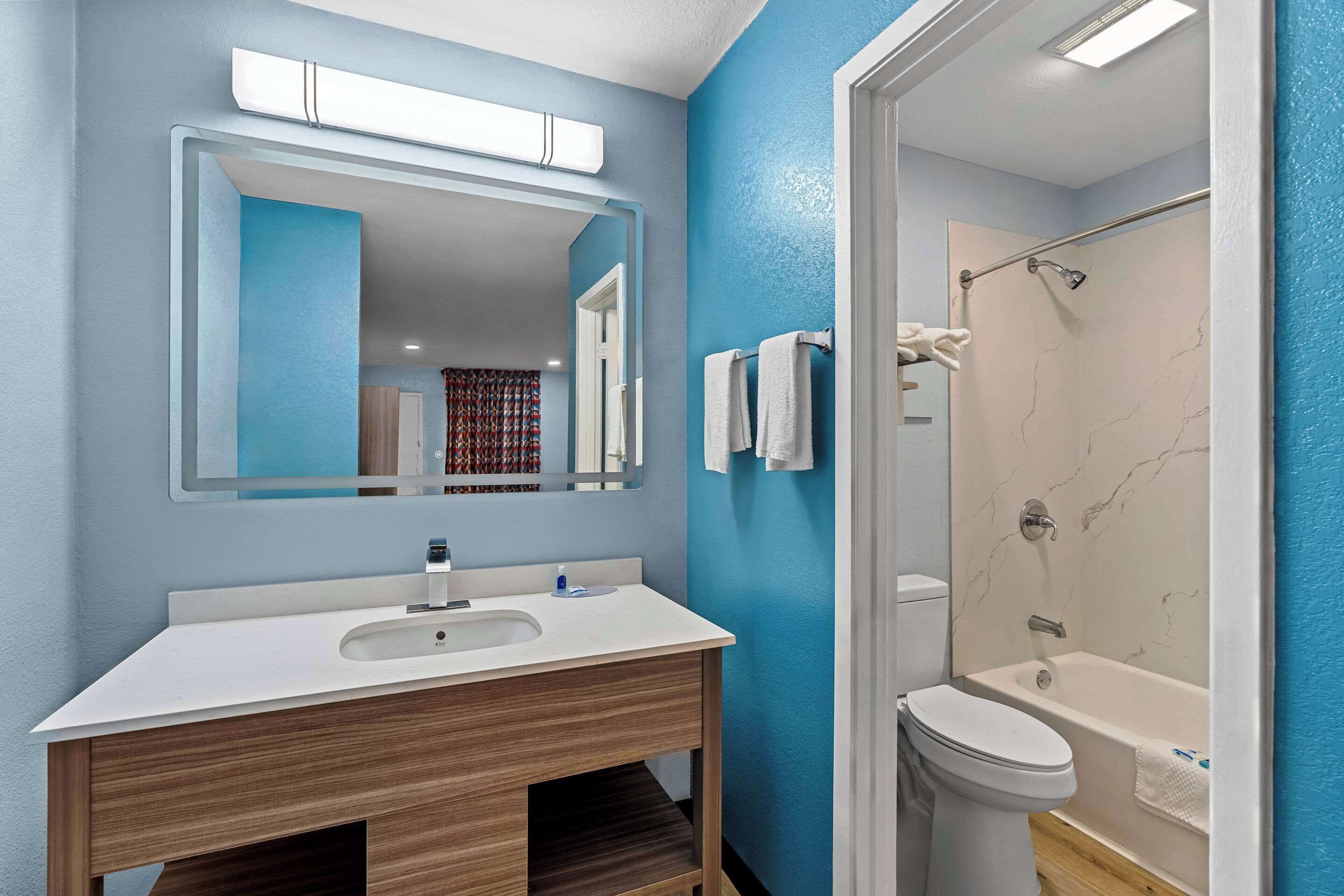 A bathroom with a white sink, mirror, and bathtub.