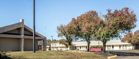 A motel named 'Rodeway Inn' with a clear sky, a parking lot, and a building with a sloped roof.