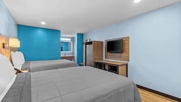 A hotel room with two beds, a TV, a desk, and a mirror.