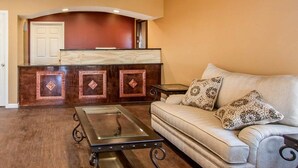 A living room with a sofa, a glass-top coffee table, and a wooden entertainment center.