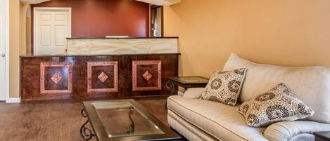 A living room with a sofa, a glass-top coffee table, and a wooden entertainment center.