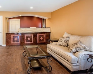 A living room with a sofa, a glass-top coffee table, and a wooden entertainment center. - Rodeway Inn & Suites Brookhaven (Brookhaven)