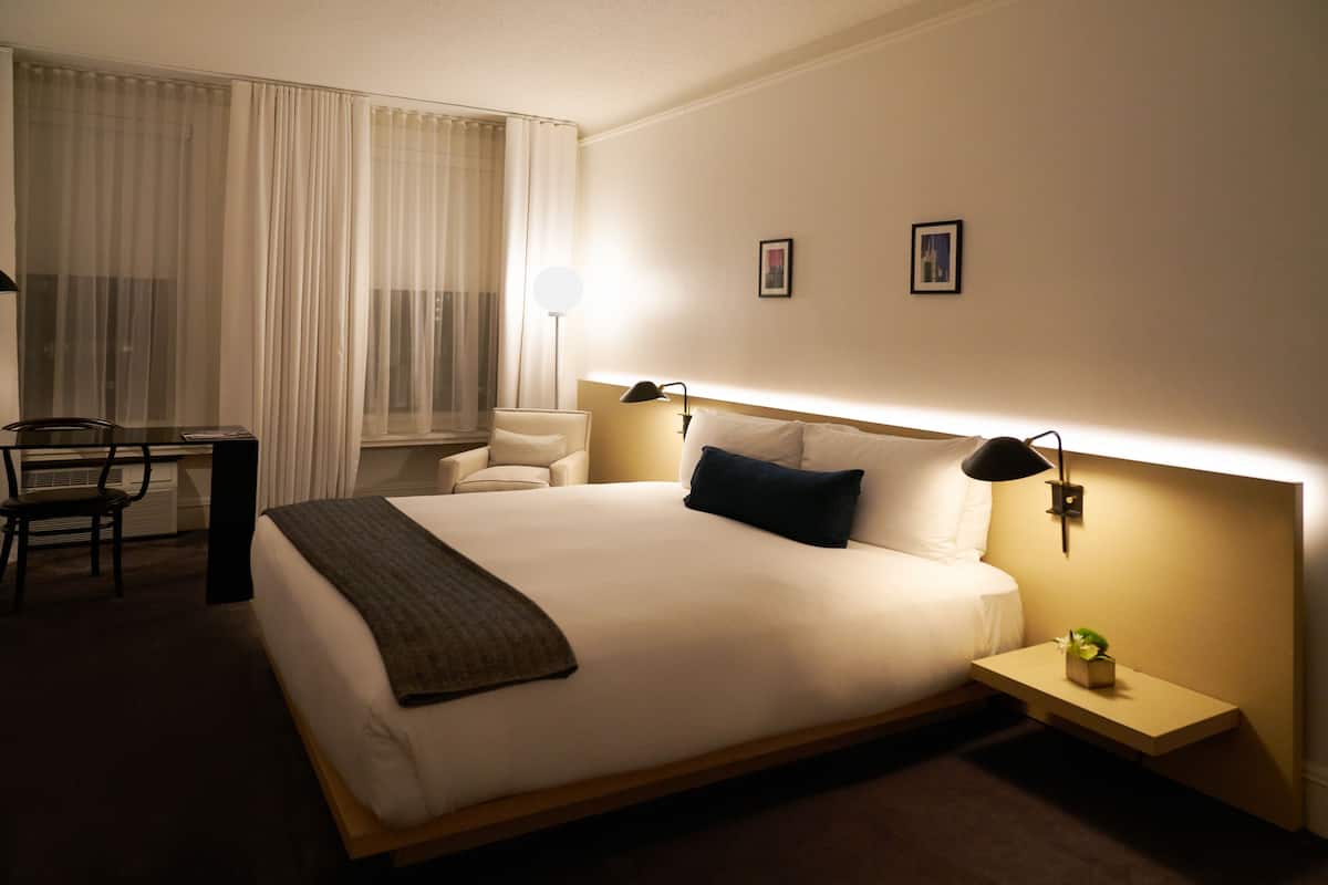 A hotel room with a large bed, bedside tables, a desk, and a chair.