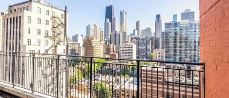 A city skyline with high-rise buildings, a fire escape, and a red brick wall.