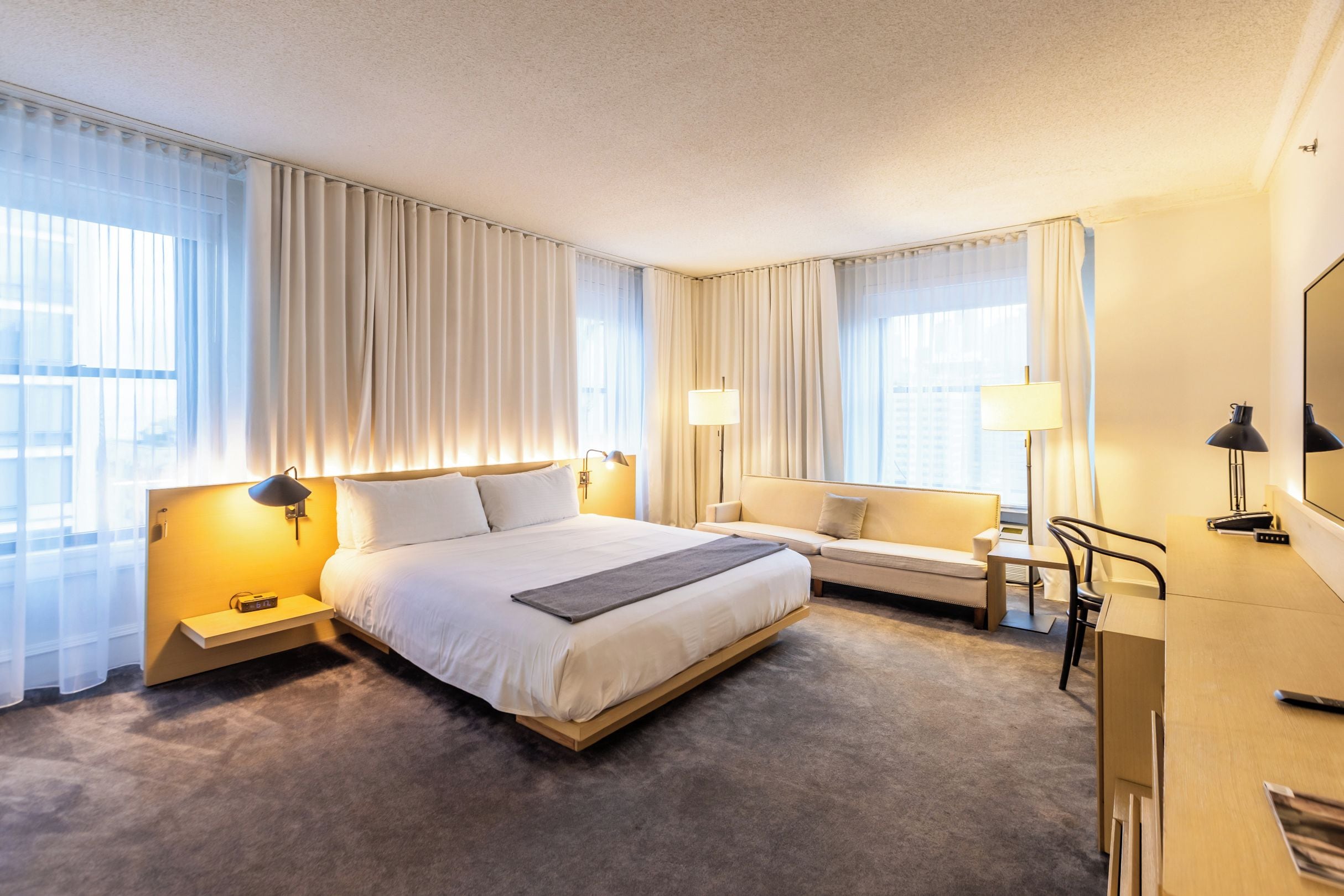 Ein Hotelzimmer mit einem großen Bett, einer Couch, einem Schreibtisch und zwei Lampen.
