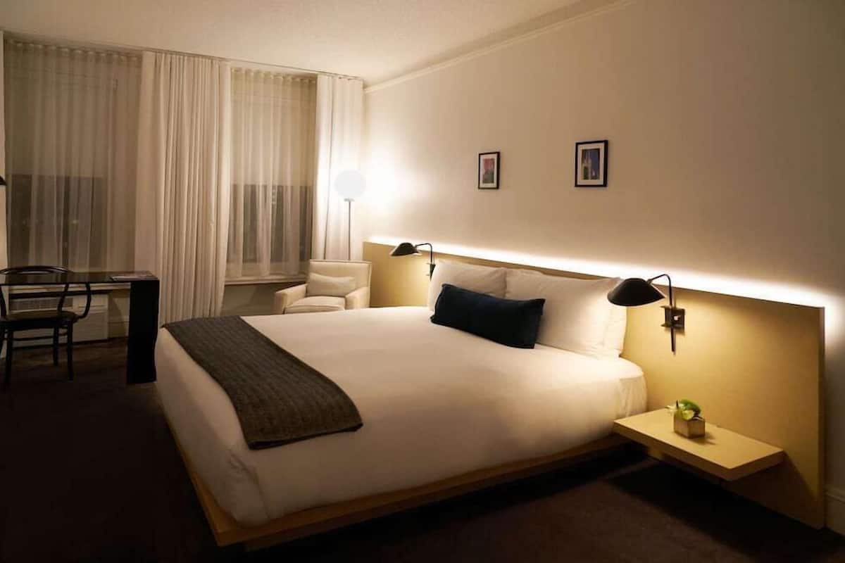 A hotel room with a large bed, bedside tables, a desk, and a chair.