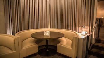 A corner seating area with a round table and two armchairs, a small table with a telephone, and a mirror on the wall.