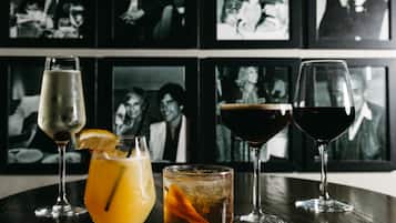 A table with three glasses of different beverages and a framed photo wall in the background.