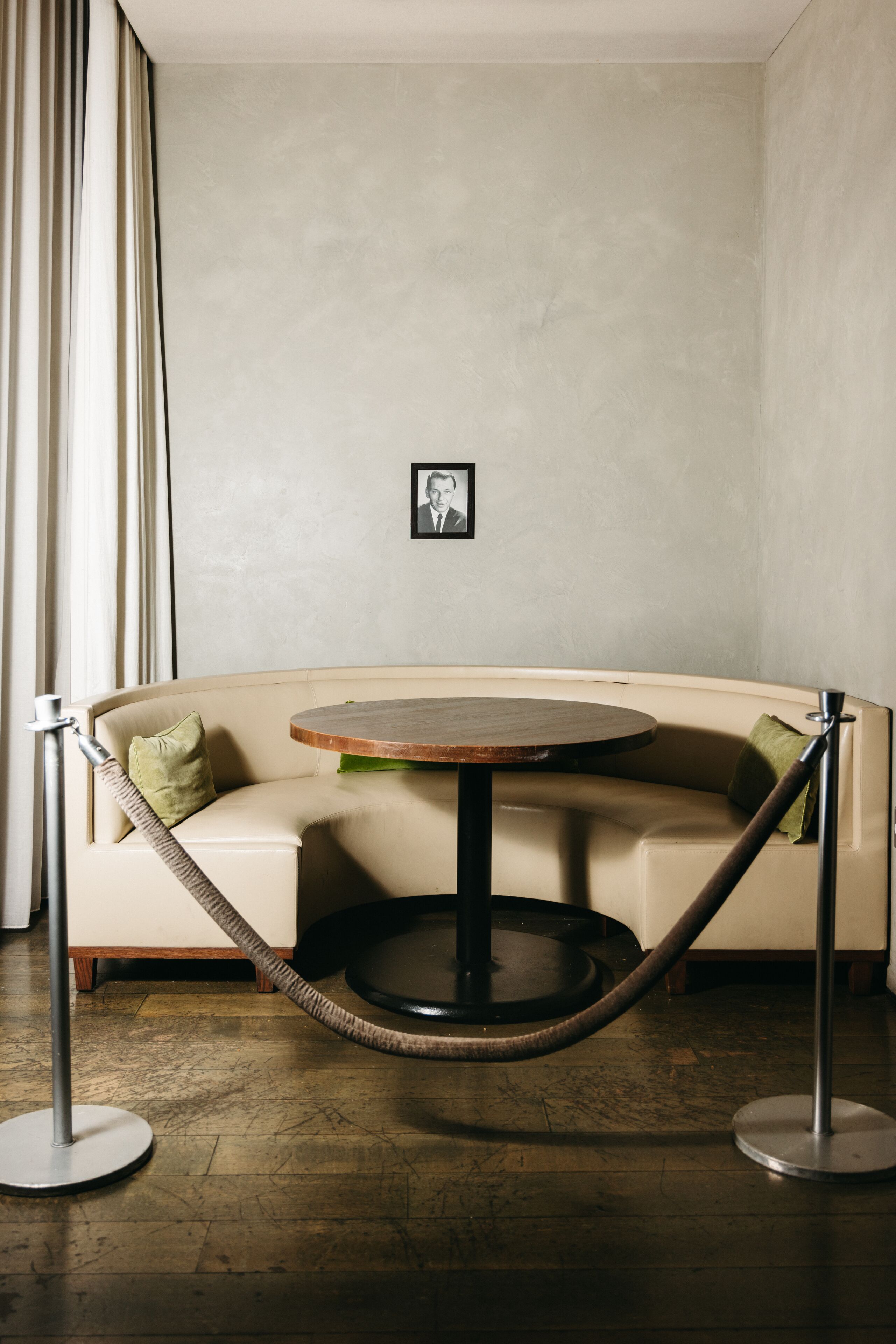 A corner seating area with a round table, a cushioned bench, and a rope barrier.