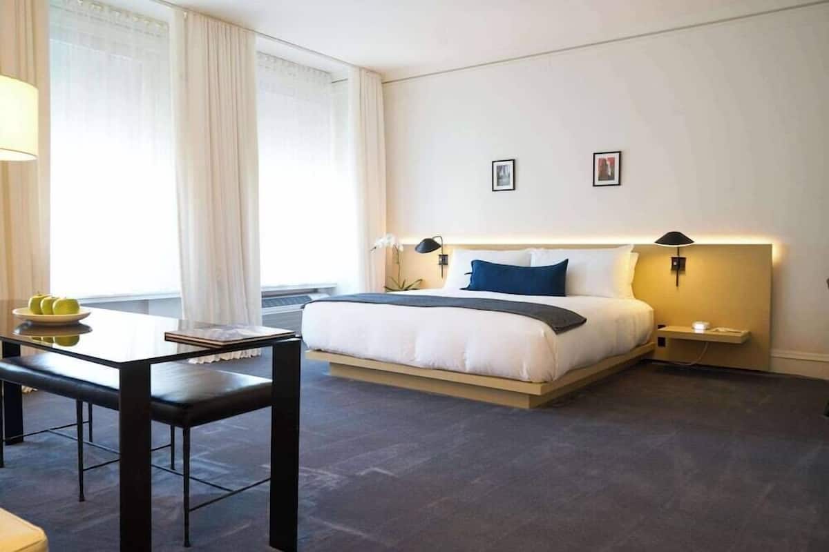 A hotel room with a bed, bedside tables, a desk, and a chair.
