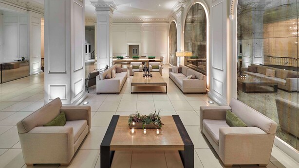 Un hall d’entrée spacieux avec une table basse centrale, des canapés et un grand miroir.