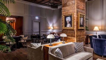 Un hall d’hôtel avec une colonne en bois, un canapé, une table et un portrait encadré.