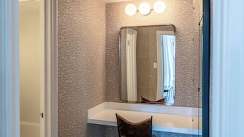 A bathroom with a vanity, a mirror, and a chair.