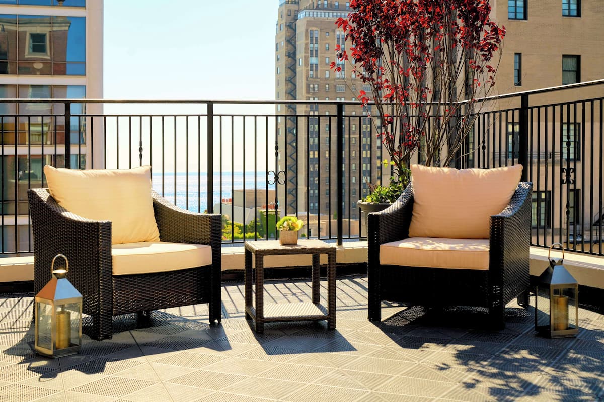 A balcony with wicker furniture, a small table, and a potted plant.