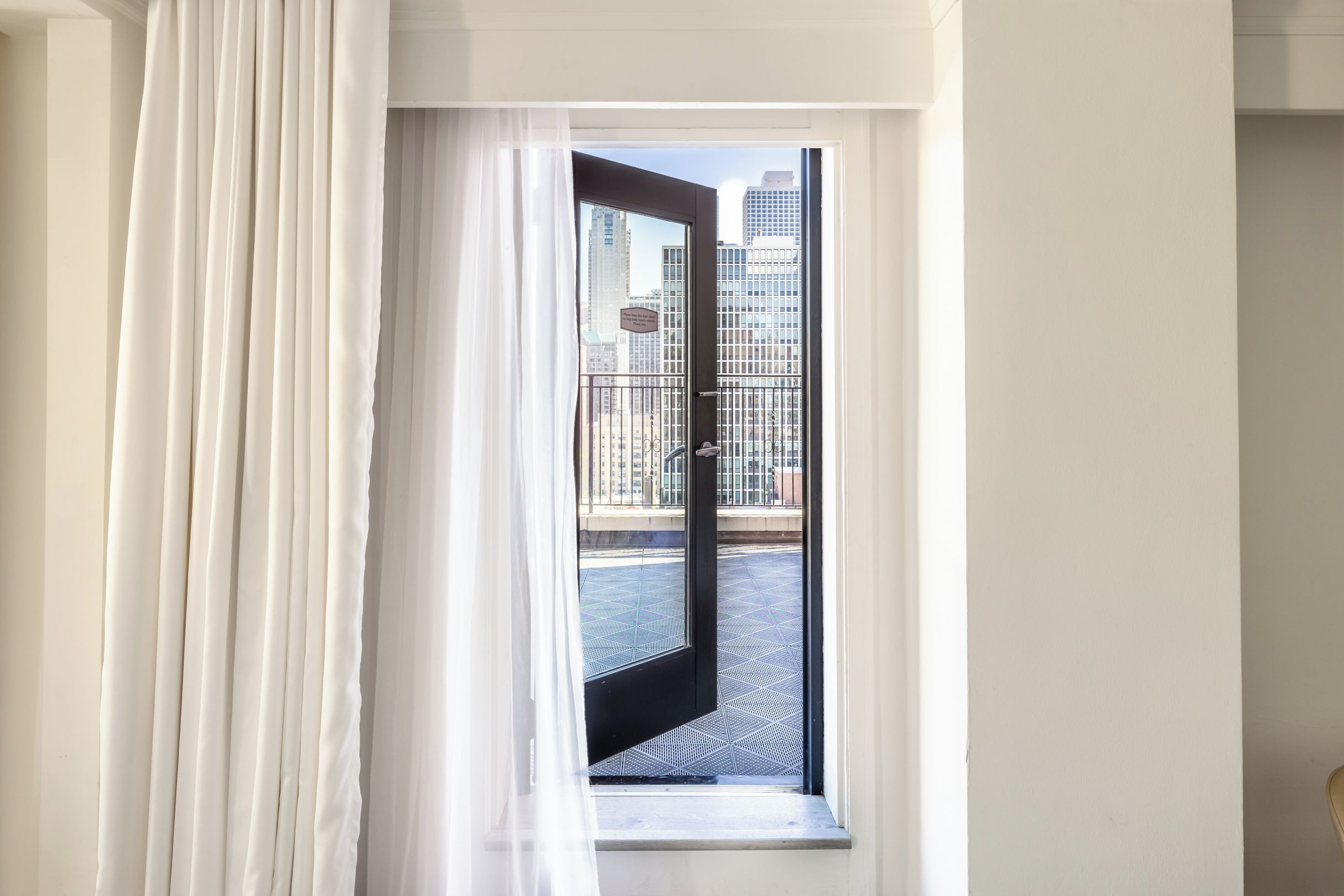 A view from a window with a metal grate floor, leading to a balcony with a metal railing.