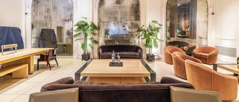 A spacious lobby with a wooden coffee table, sofas, and armchairs.
